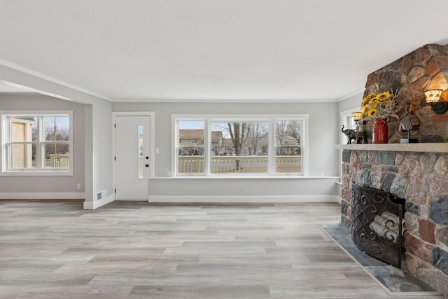 unfurnished living room with light hardwood / wood-style floors, crown molding, and a fireplace