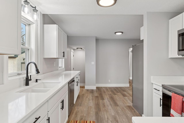 kitchen featuring light hardwood / wood-style flooring, sink, white cabinets, a textured ceiling, and stainless steel appliances