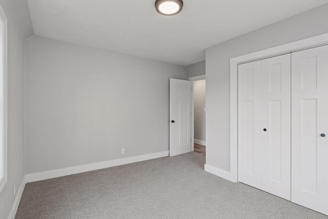 unfurnished bedroom featuring light colored carpet and a closet