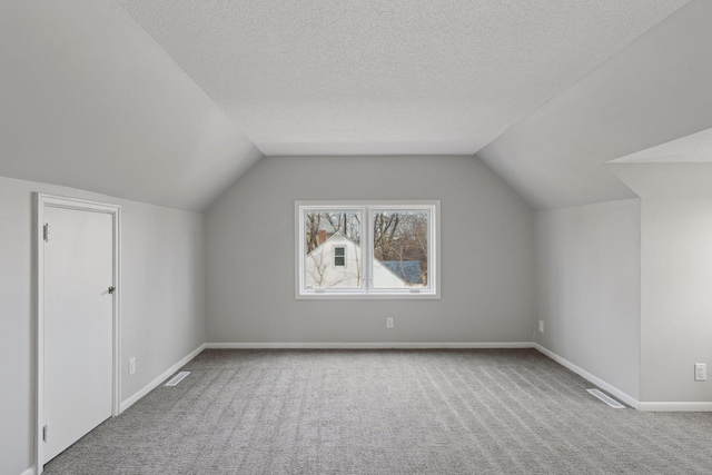 bonus room with a textured ceiling, vaulted ceiling, and carpet floors