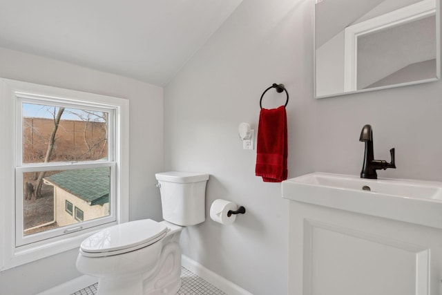 bathroom with tile patterned flooring, toilet, vanity, and vaulted ceiling