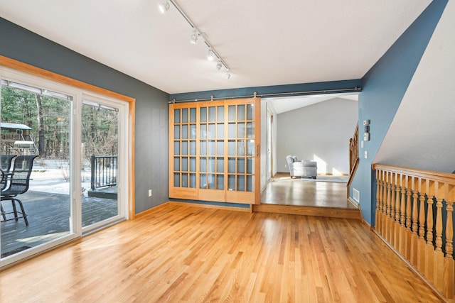 unfurnished room with hardwood / wood-style flooring, lofted ceiling, and a barn door