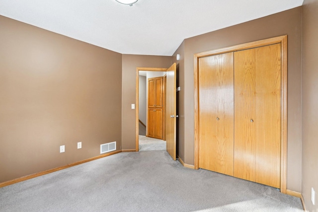 unfurnished bedroom featuring light colored carpet and a closet