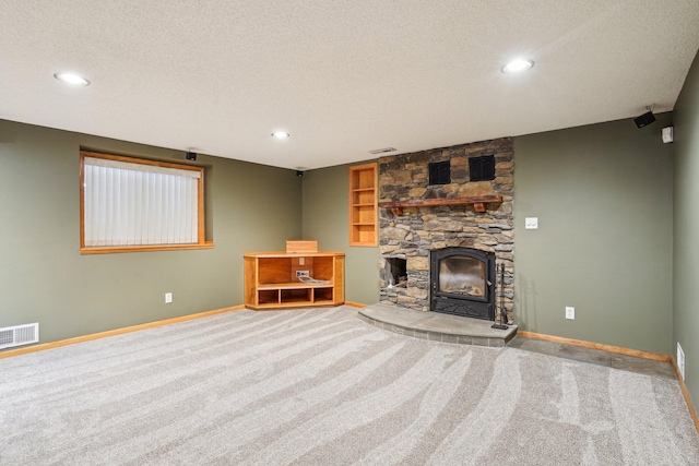 unfurnished living room with light colored carpet, a textured ceiling, and a fireplace