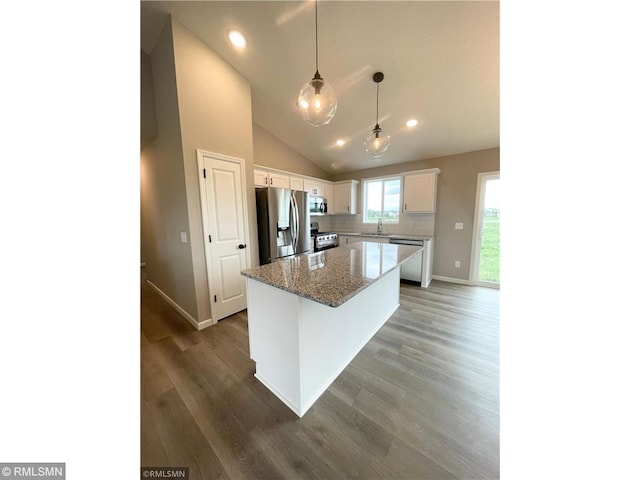 kitchen featuring a center island, white cabinets, decorative backsplash, light stone countertops, and appliances with stainless steel finishes