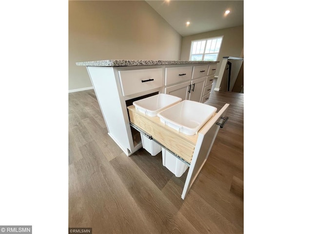 kitchen featuring white cabinets, a center island, light hardwood / wood-style flooring, and vaulted ceiling