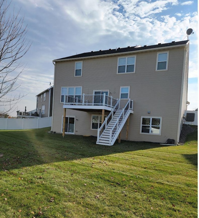 rear view of house featuring a wooden deck and a yard