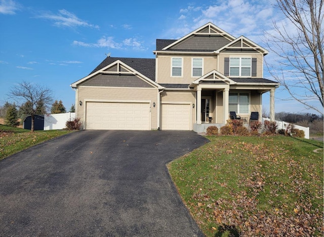 view of front of property with a garage, a front yard, and covered porch