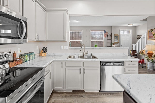 kitchen featuring light hardwood / wood-style floors, sink, white cabinetry, stainless steel appliances, and light stone counters