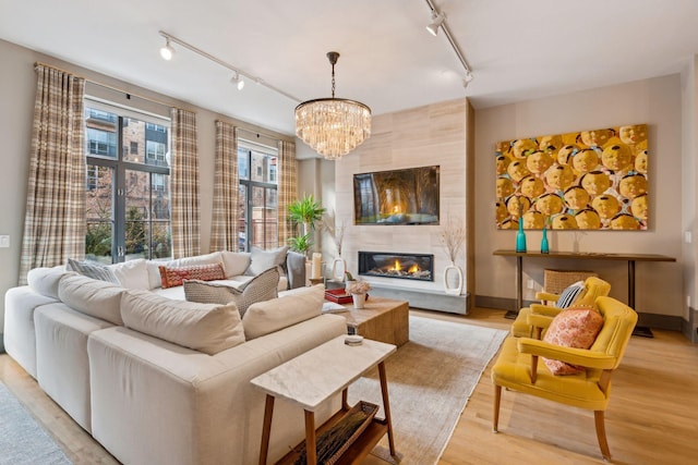 living room featuring a large fireplace, a chandelier, and light hardwood / wood-style flooring