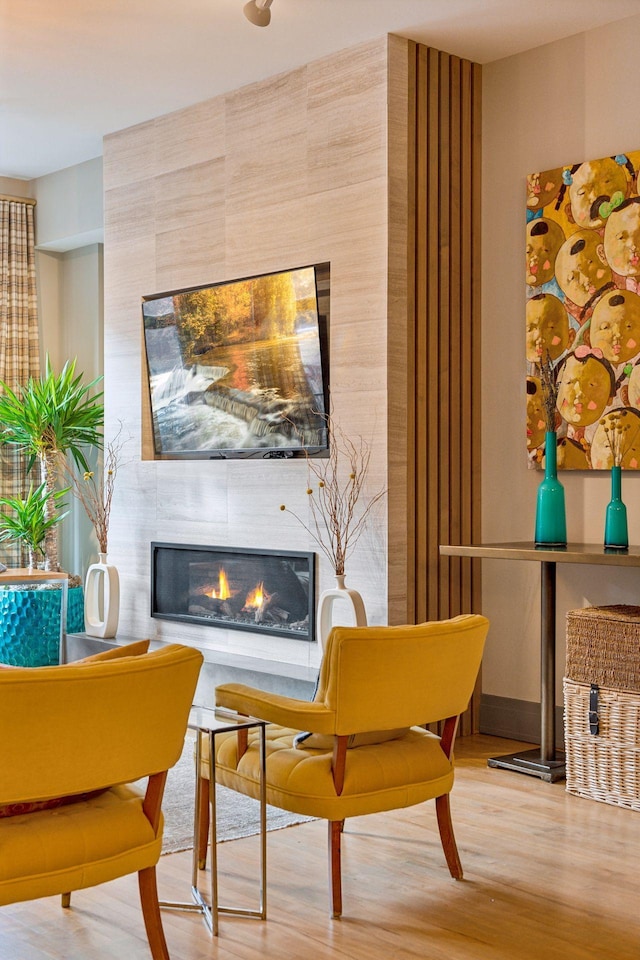 living area with wood-type flooring and a tiled fireplace