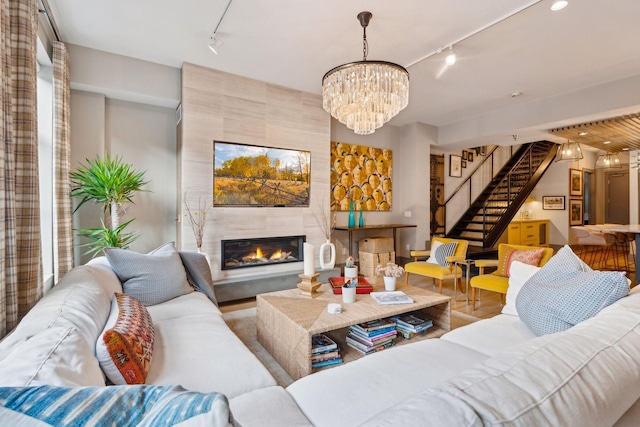 living room with track lighting, a chandelier, and a tile fireplace