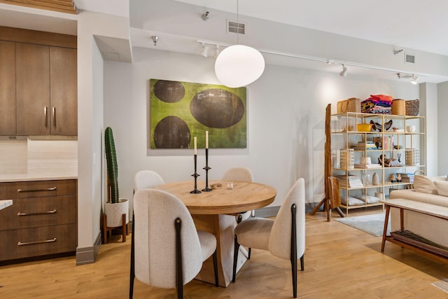 dining space with light hardwood / wood-style floors and track lighting