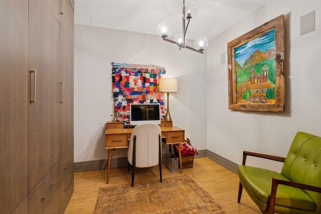 home office featuring light hardwood / wood-style floors and an inviting chandelier