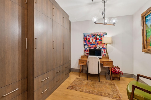 home office with a notable chandelier and light hardwood / wood-style flooring