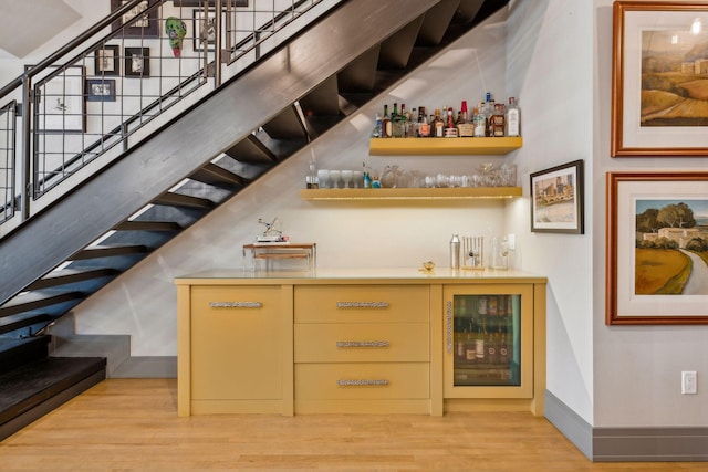 bar featuring beverage cooler and light hardwood / wood-style flooring