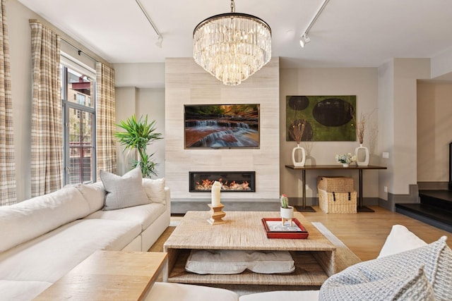 living area with an inviting chandelier, a fireplace, rail lighting, and wood finished floors