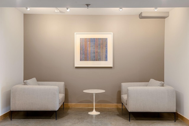 living area with baseboards and concrete flooring