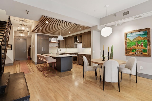 dining room with light wood-type flooring, stairs, baseboards, and visible vents