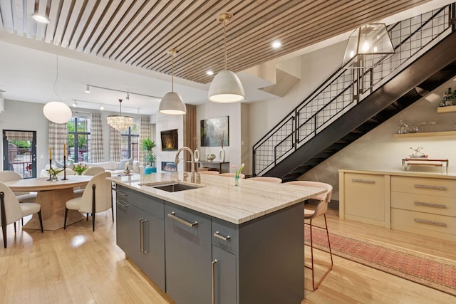 kitchen with light wood-style floors, a sink, an island with sink, and open floor plan