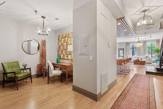 hall with light wood-style floors, baseboards, visible vents, and a chandelier