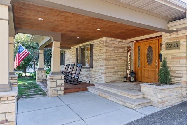 view of exterior entry with stone siding and covered porch