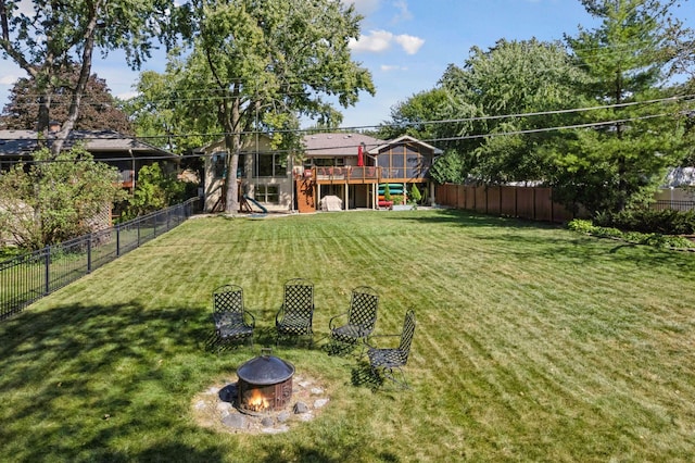 view of yard with a wooden deck, stairway, a fire pit, and a fenced backyard