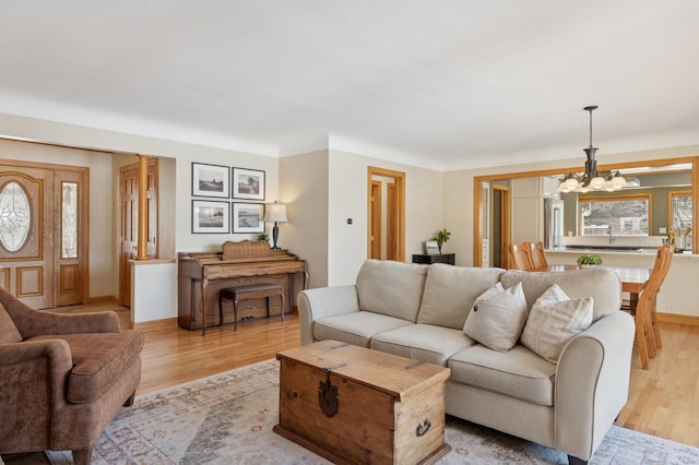 living room featuring baseboards, light wood finished floors, and a chandelier