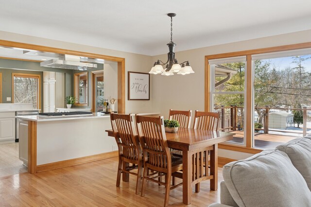 dining space with a notable chandelier, baseboards, and light wood-style floors