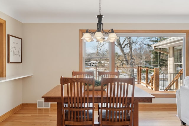 dining room with an inviting chandelier, light wood-style flooring, baseboards, and visible vents