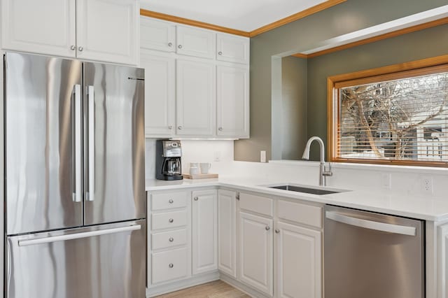 kitchen featuring light countertops, ornamental molding, appliances with stainless steel finishes, white cabinets, and a sink