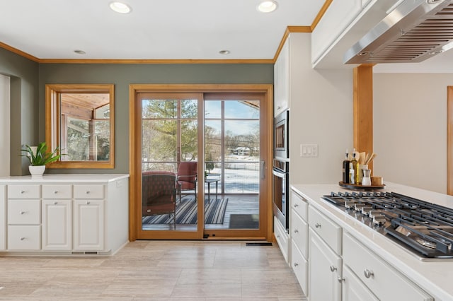 kitchen featuring white cabinetry, stainless steel appliances, wall chimney exhaust hood, and light countertops