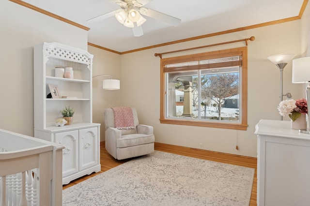 bedroom featuring light wood-style flooring, a crib, baseboards, and ornamental molding