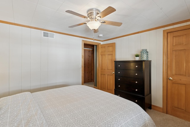 carpeted bedroom with crown molding, visible vents, and ceiling fan