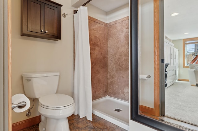 full bathroom with baseboards, toilet, and a shower stall