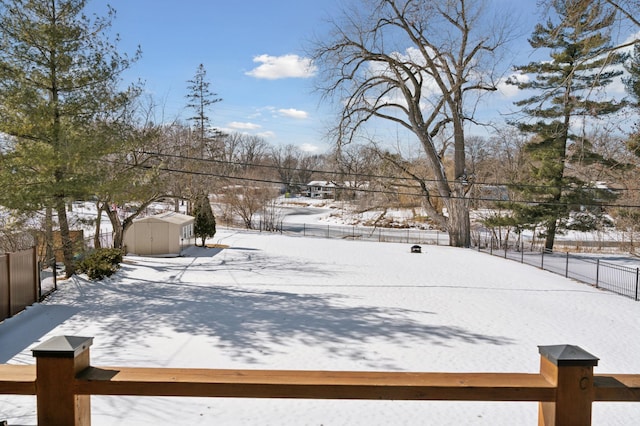 yard layered in snow featuring fence, an outdoor structure, and a shed