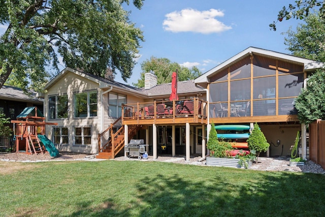 rear view of house featuring stairway, a sunroom, a chimney, a deck, and a yard