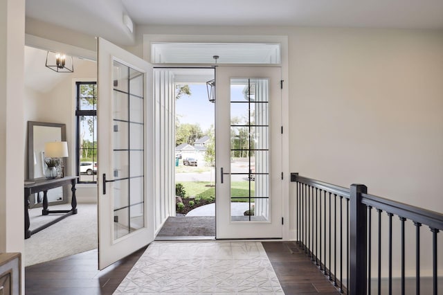 doorway with a notable chandelier, dark hardwood / wood-style floors, vaulted ceiling, and french doors