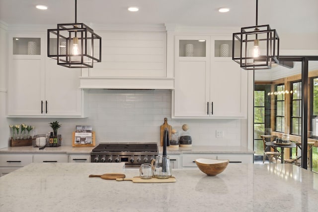 kitchen featuring pendant lighting, light stone counters, white cabinetry, and stove