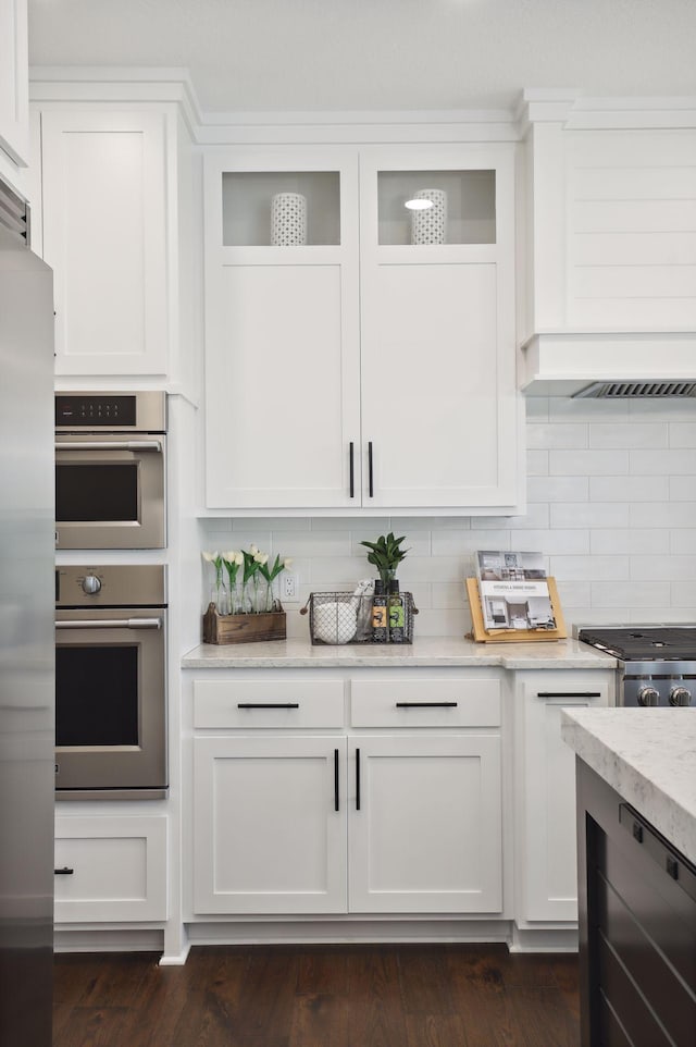 kitchen with decorative backsplash, dark hardwood / wood-style floors, white cabinetry, and stainless steel appliances