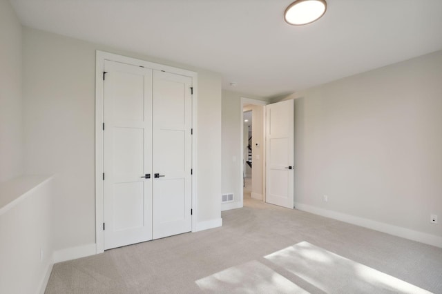 unfurnished bedroom with light carpet and a closet