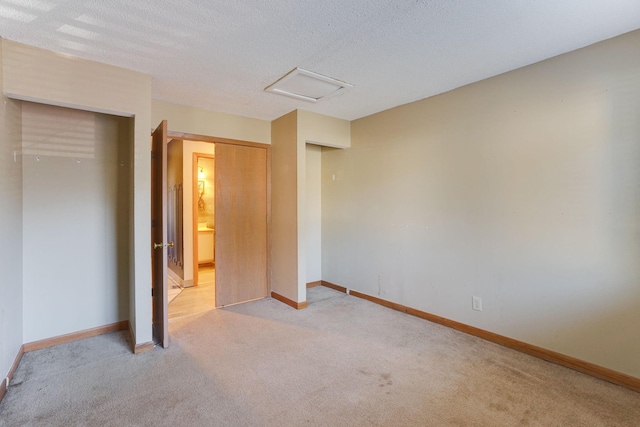 unfurnished bedroom featuring light carpet, a textured ceiling, and a closet