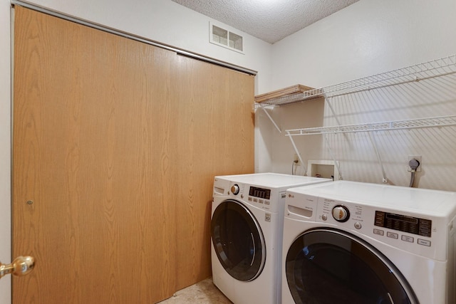 laundry area featuring a textured ceiling and washing machine and dryer