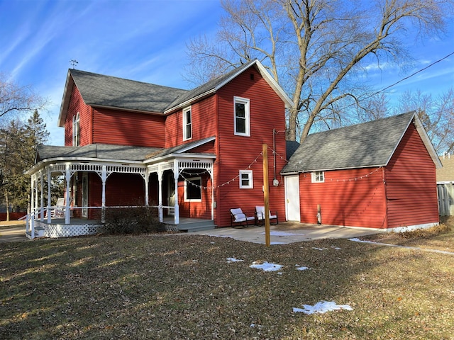 back of property with covered porch, a yard, and a patio area