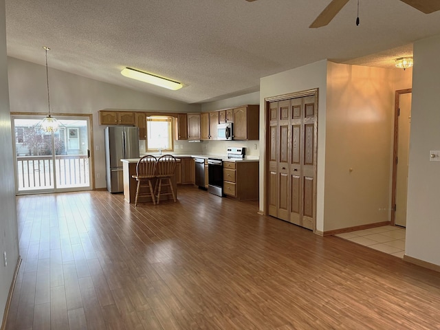 kitchen featuring a center island, stainless steel appliances, light hardwood / wood-style flooring, decorative light fixtures, and a kitchen bar