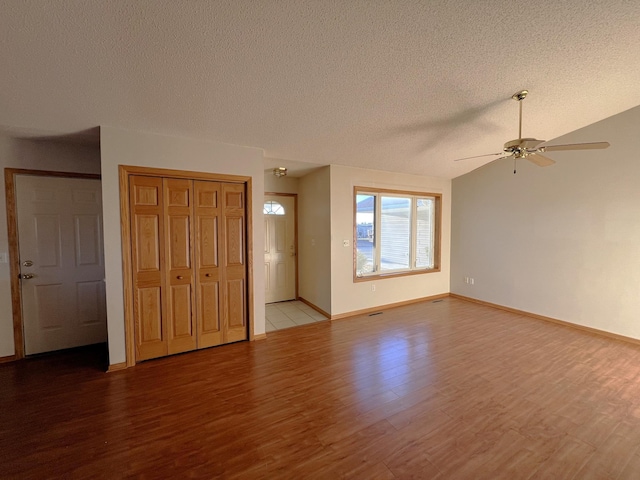 unfurnished living room featuring a textured ceiling, ceiling fan, lofted ceiling, and light wood-type flooring