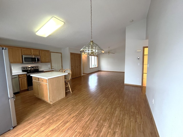 kitchen with a center island, stainless steel appliances, decorative light fixtures, ceiling fan with notable chandelier, and light wood-type flooring