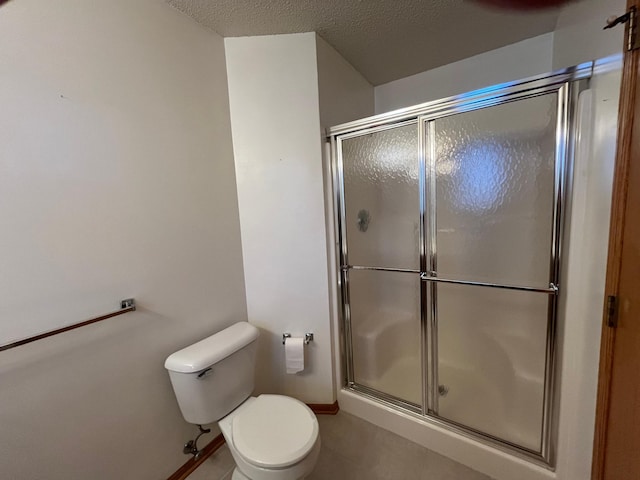 bathroom with tile patterned floors, toilet, a textured ceiling, and walk in shower