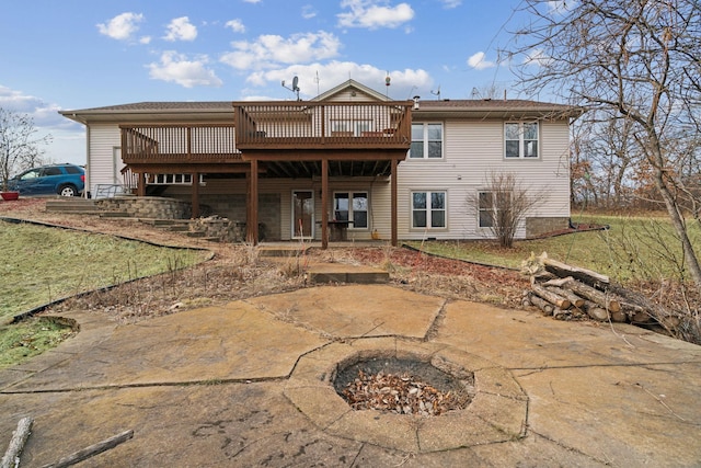 rear view of property with a wooden deck and an outdoor fire pit