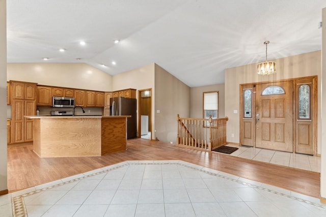 entryway with light tile patterned flooring, vaulted ceiling, sink, and an inviting chandelier